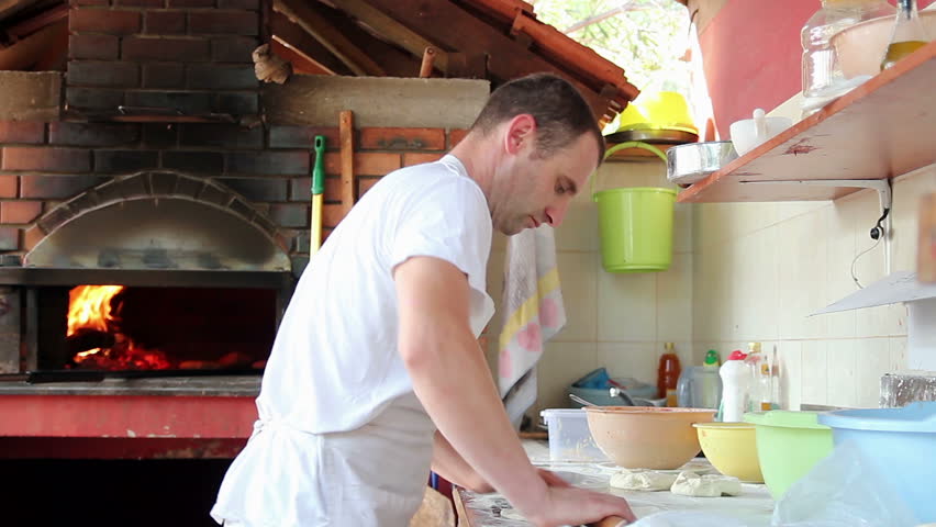 Chefs making pizza in commercial kitchen.