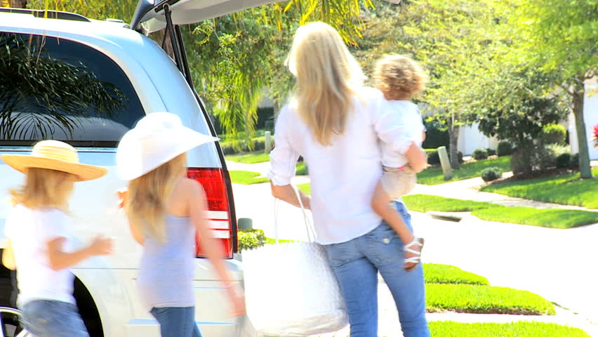 Happy young Caucasian family packing family car going to beach