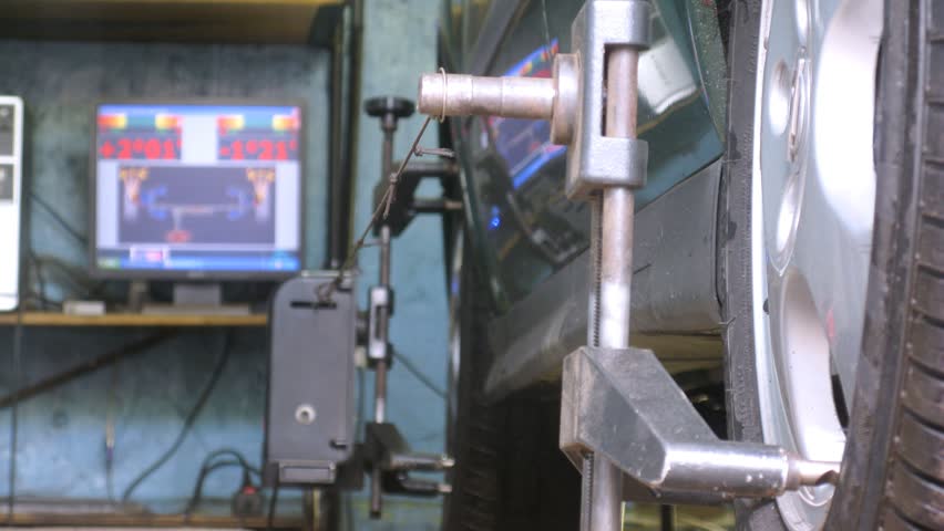 Mechanic tests wheel alignment camber of car on computer in car-care center, time lapse