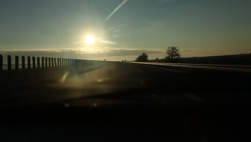 Can runs on highway at sunrise and passes under bridges or crossroads. Dramatic sun and clouds look.
