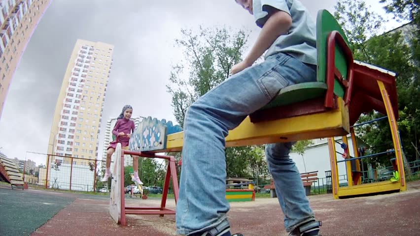 Girl and boy goes for a drive on teeterboard in house yard