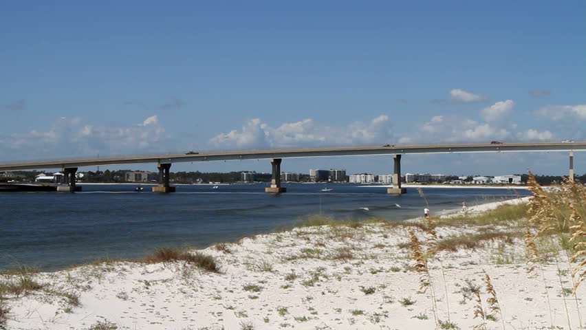 Traffic moves across the inter-coastal waterway on route 98 bridge at Perdido Pass with dunes and sea oats in the foreground and condominiums in the background all part of Orange Beach, Alabama.