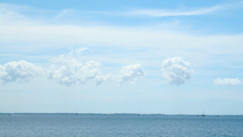 Timelapse of clouds and watercraft moving over the horizon with water.