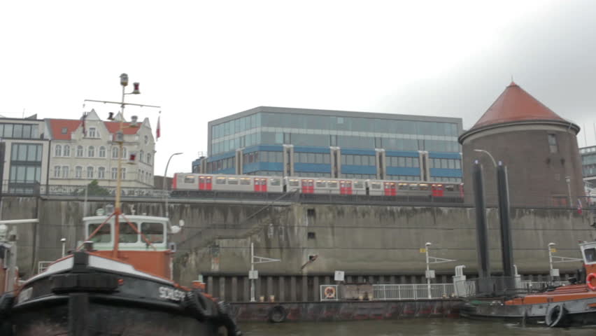 HAMBURG - JUNE 3, 2012: Sail across the Elbe river at a rainy day. Subway train is passing by behind.