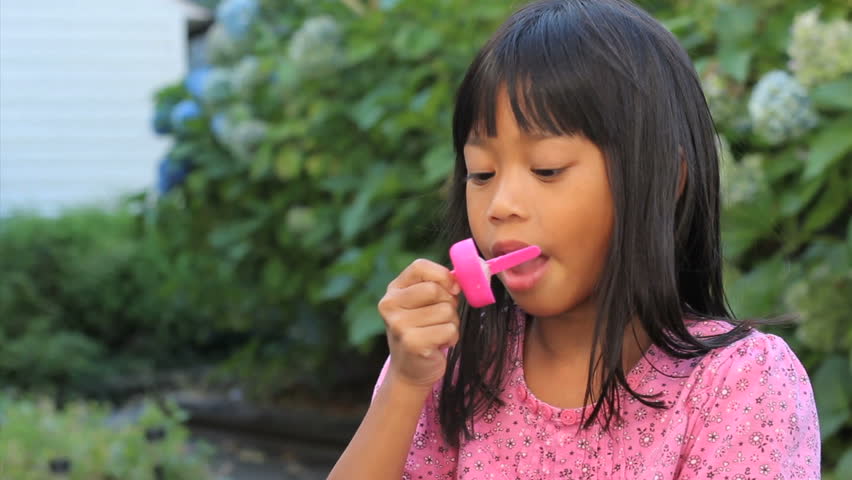 A Cute Little 6 Year Old Asian Girl Enjoys Licking Her Popsicle On A 