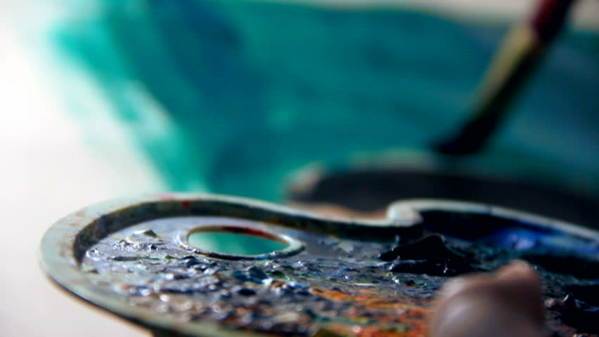 Painter painting with watercolors, blue, green on white drawing. Holding palette with colours. HD1080p.