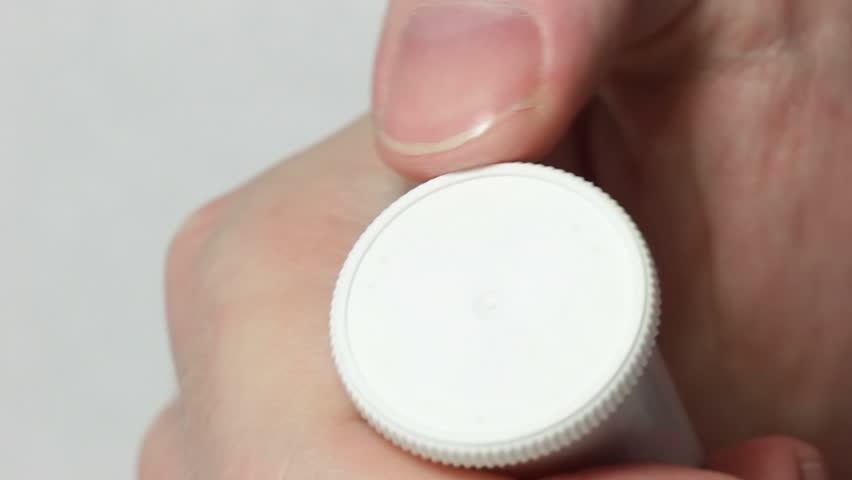 Hand opens a white vial