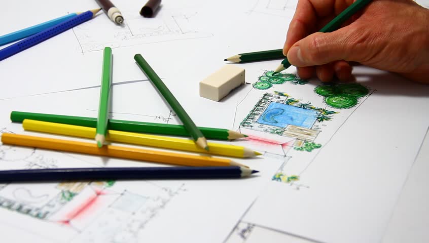 Man sketching on landscape architectural drawing with crayon.