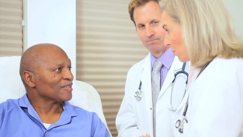 Portrait Caucasian male female hospital doctors reassuring senior ethnic patient