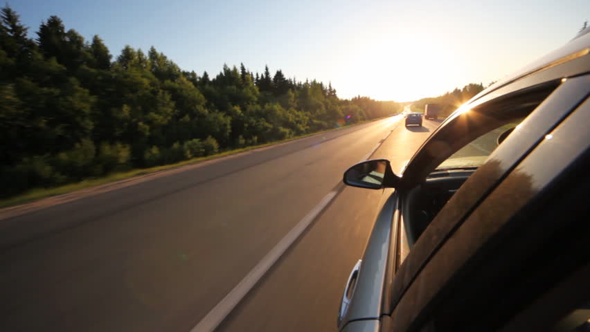 car goes on bilateral road among wood behind other cars