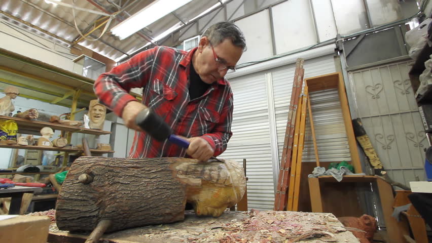 Wood artist working on an Indian figure with his chisel