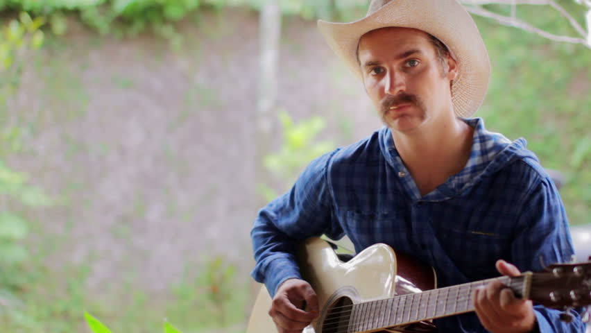 cool Caucasian man playing guitar wearing cowboy hat
