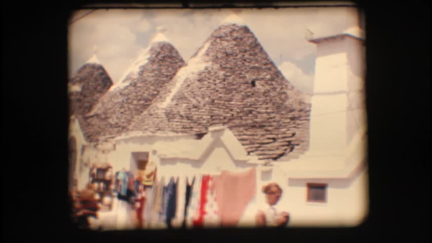 Vintage 8mm. Typical cone shaped houses (trullo) and tourists in Alberobello, a unique Italian town
