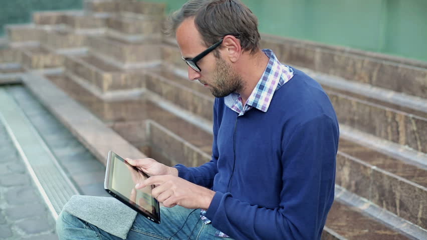 Young man with tablet computer in the city, steadicam shot
