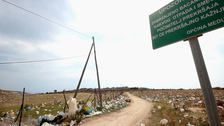 Dirty road. Road by the landfill with the warning sign
