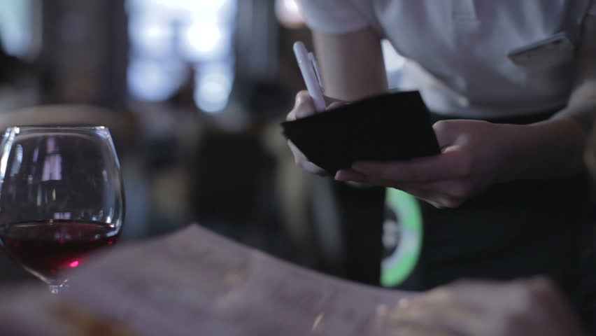 Girl makes an order from menu in restaurant