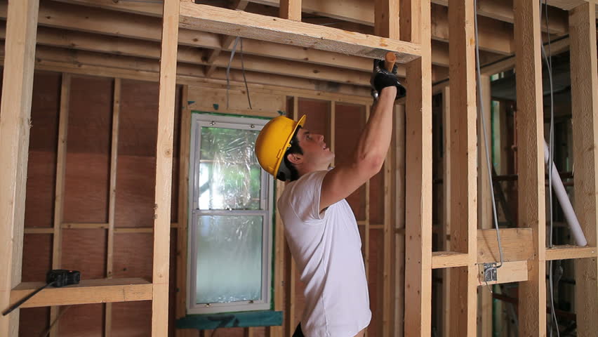 Builder hammering door frame in house construction site
