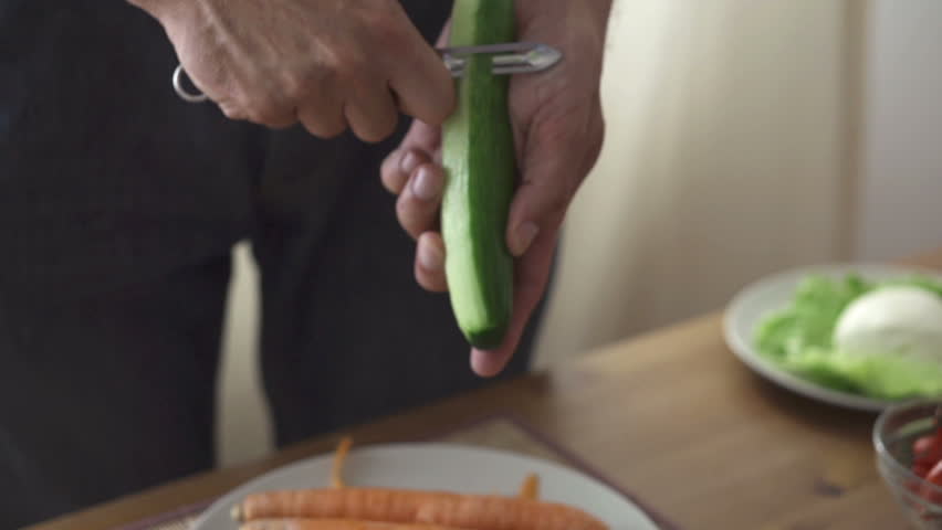 Male hands peeling cucumber, slow motion shot at 240fps
