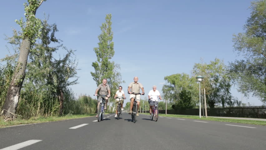 four seniors biking on street
