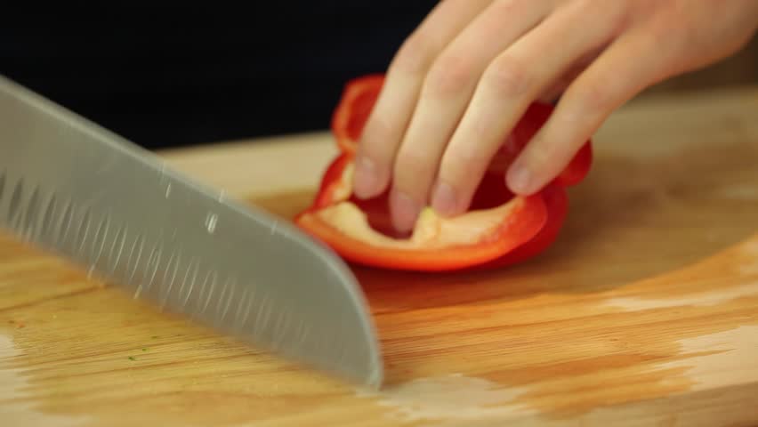 Dolly shot of female hands cutting paprika in kitchen surrounding
