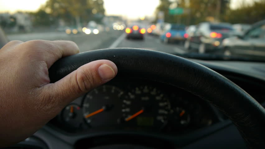 Driving at Sunset on the freeway. Traffic Jam. Mirror with sunset background. Hand on steering wheel close up. pov. edited sequence.