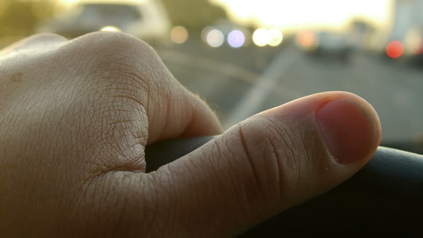 Driving at Sunset on the freeway. Traffic Jam. -Hand on steering wheel close up.