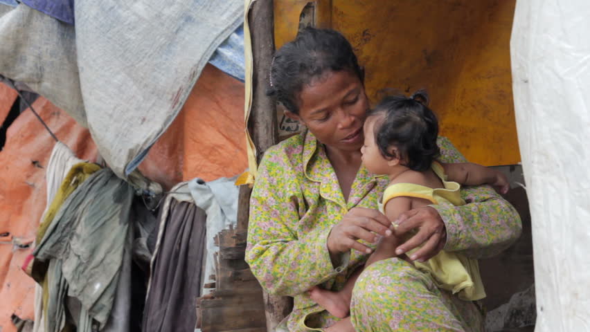 Mother feeding baby in Cambodian slums, close to dump area