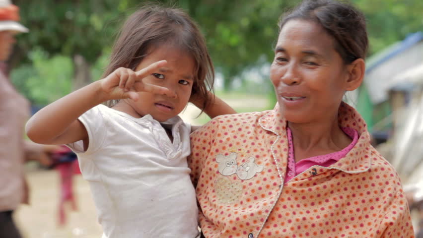 Mother holding baby in Cambodian shanty, close to dumping area