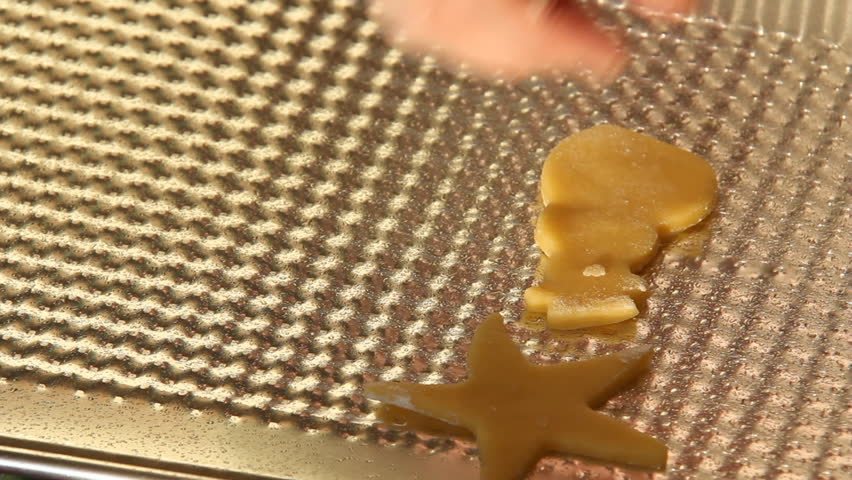 Baking Sugar Cookies 14. Preparing, mixing, baking and decorating Christmas sugar cookies. Placing prepared cookies of different shapes onto a cookie sheet.
