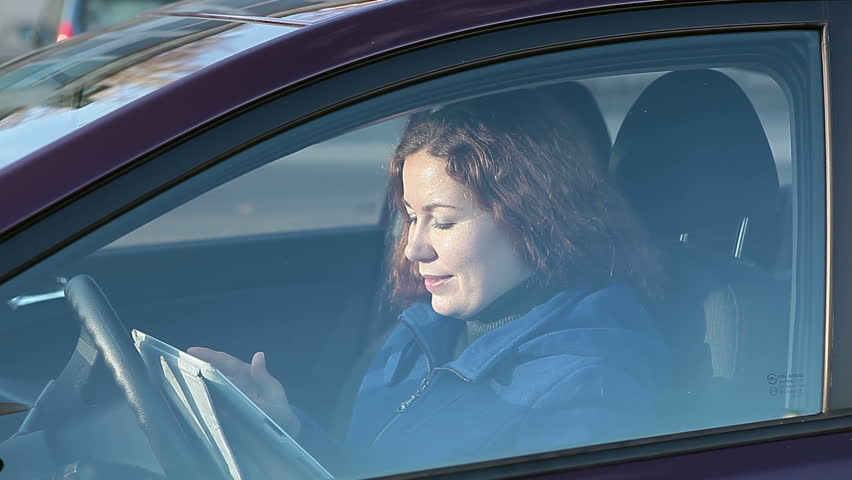Woman using tablet pc behind closed car window glass