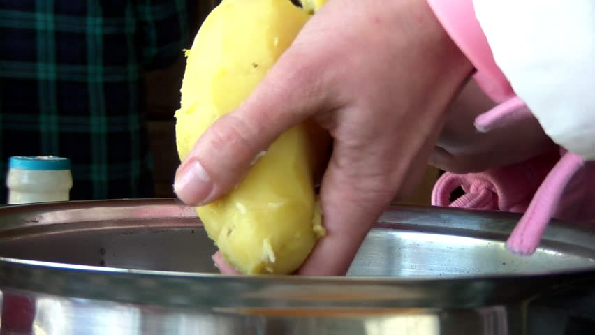 Female hands pealing cooked potatoes
