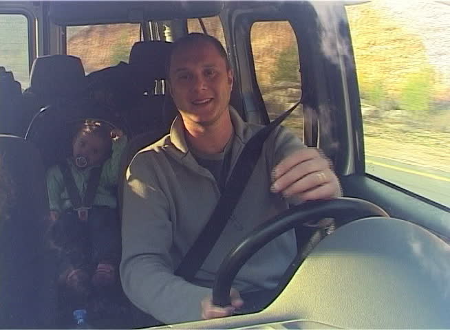 Father driving a car, Girl sitting on the rear seat.