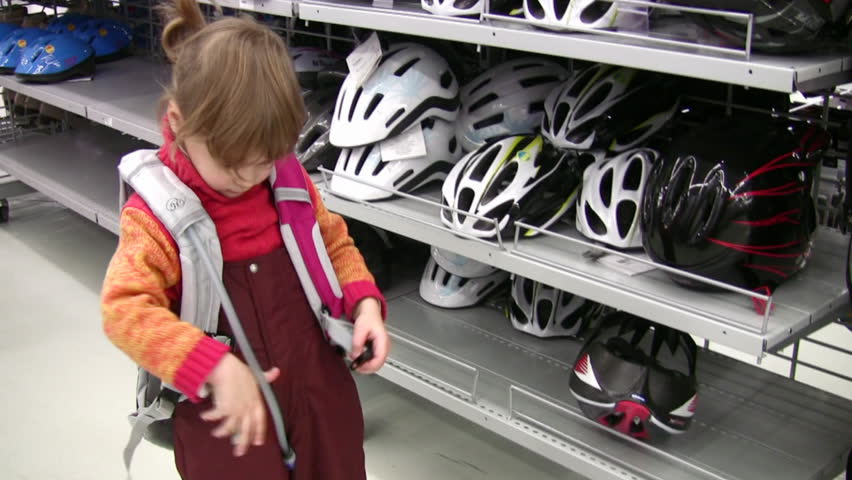 little girl with knapsack in shop, bicycle helmets 