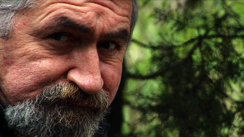 Senior bearded man eating and chewing outdoors
