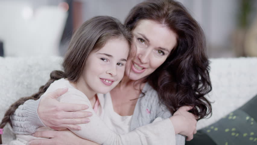 A soft and feminine close up of mother and daughter looking directly into camera. In slow motion.
