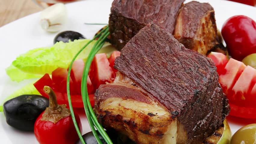 savory food : roast beef garnished with apple juice green and black olives red hot peppers on wooden table