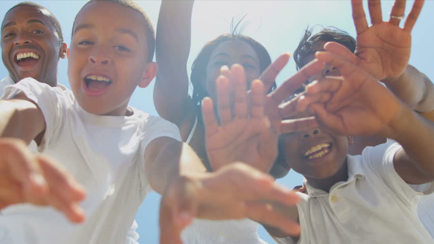 Close up of ethnic family waving on video call together on beach