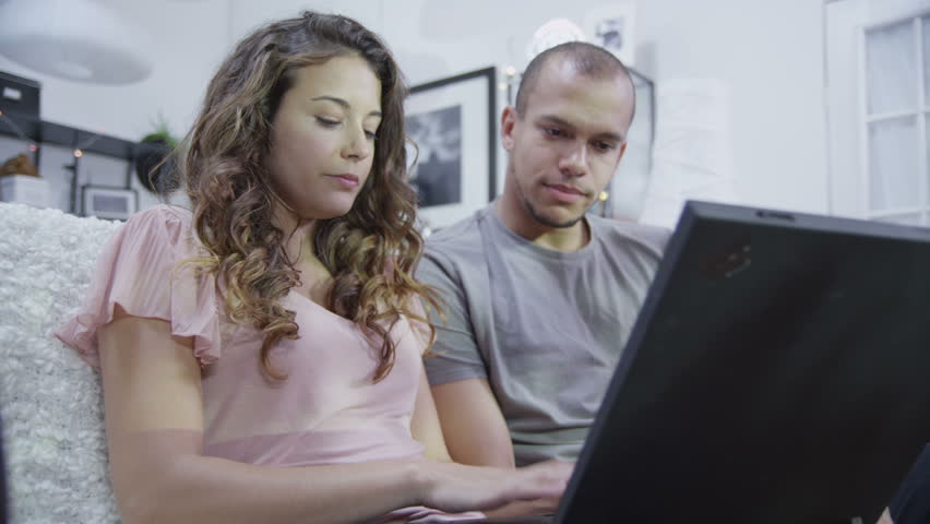 Attractive couple checking lottery numbers on line discover that they are winners. In slow motion.