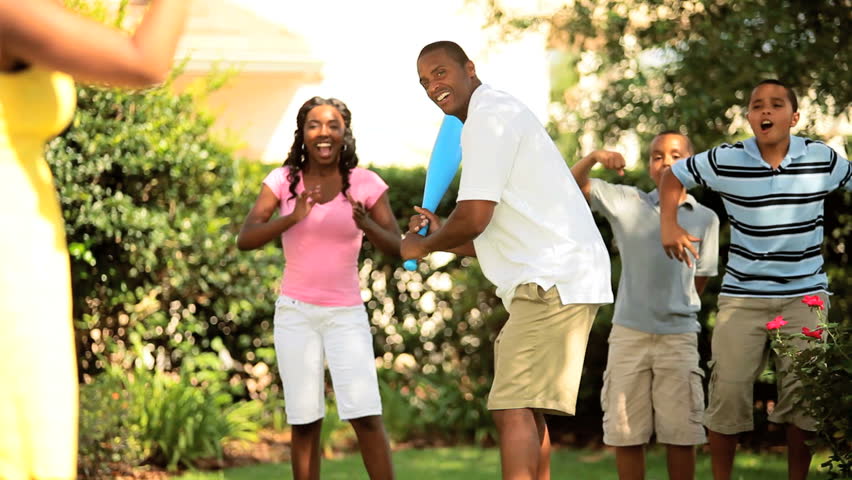 Friendly baseball game of ethnic family in garden