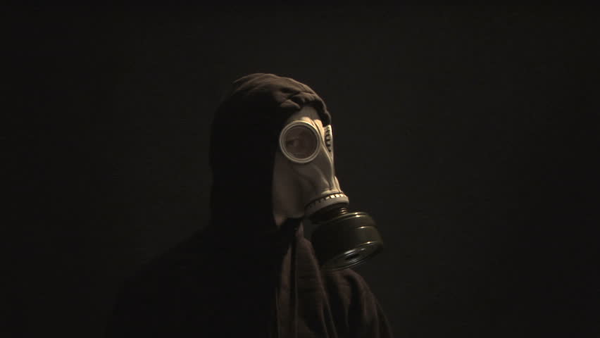 Smoke rising behind a man in a gas mask