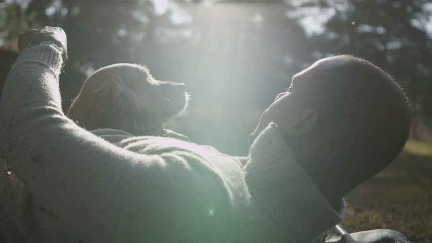 A man and his lovable pet dog laying down together in the early morning sunshine