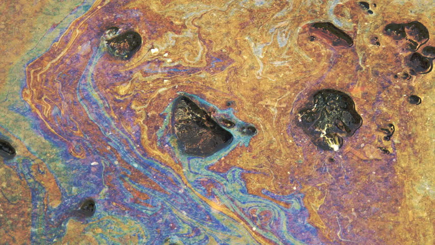 Toxic petroleum-based film on puddle, blown by wind.