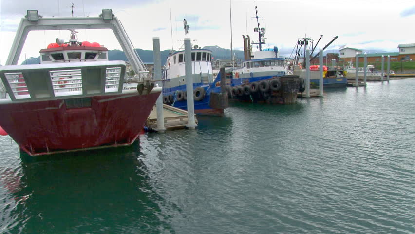 KACHEMAK, AK - CIRCA 2012: Passing by on boat, tracking scene of the marina with two large working/tug boats