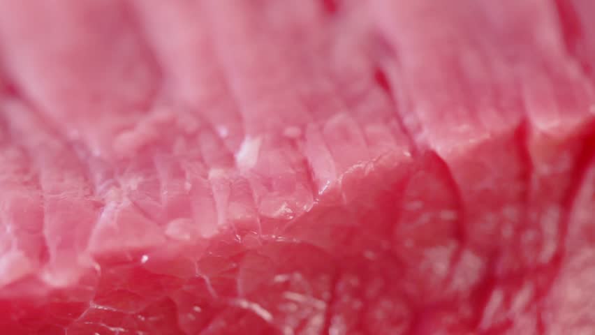 Piece of fresh red uncooked meat flesh spins closeup