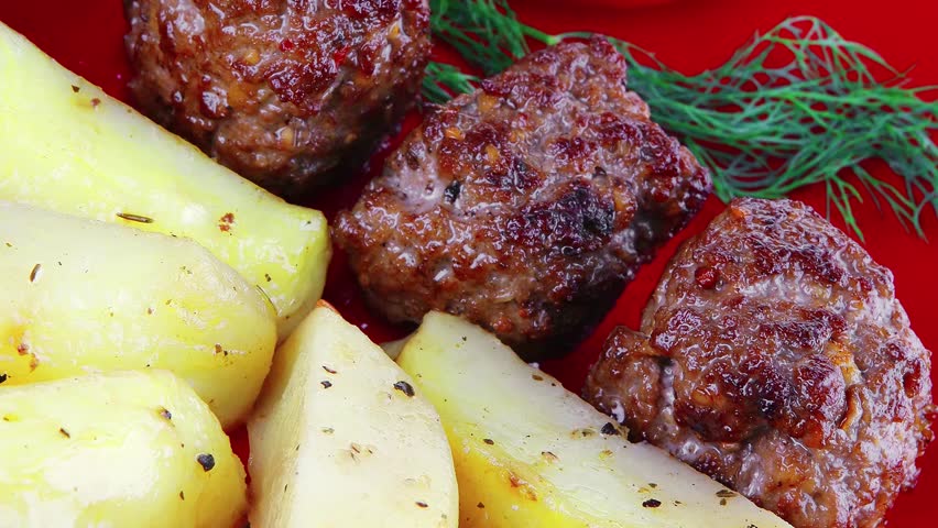 roast cutlets on red dish with peppers and potatoes