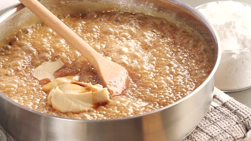 Peanut butter fudge being made: peanut butter being stirred into milk caramel