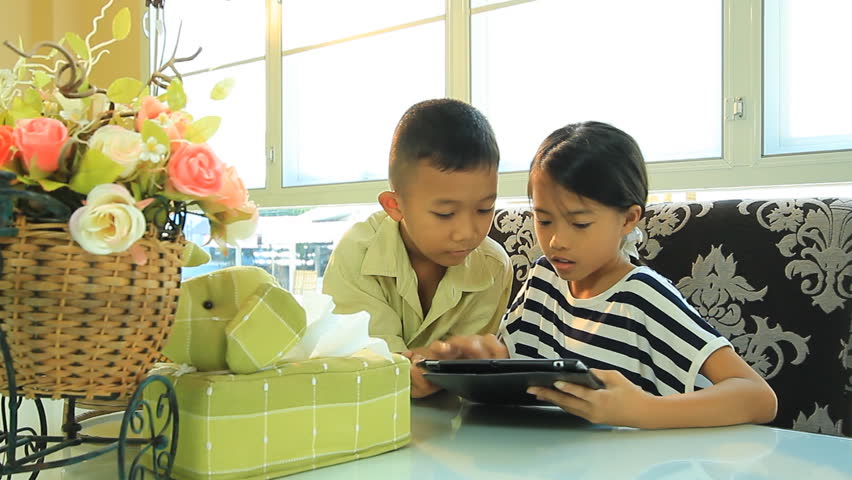 Asian boy and girl with a tablet computer in the living room.