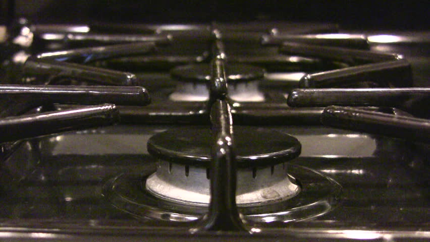 HD 1080i shot of a gas stove igniting and warming a stainless steel saucepan.