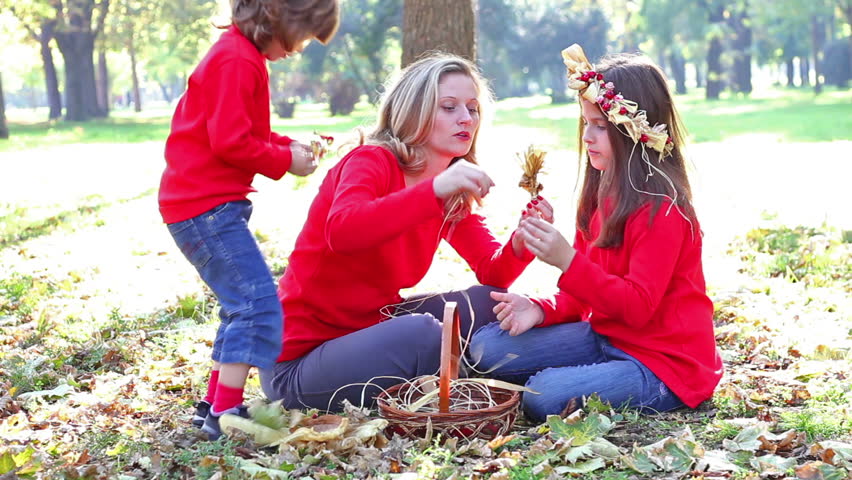 Mom and daughter in the park make a garland of flowers, Focus on the mum and children