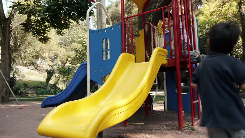 Two Hispanic Latino Brothers Playing on a Public Park Slide.